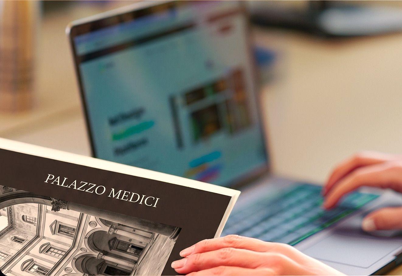 Una mano sfoglia un libro illustrato accanto a un portatile: lo studio universitario in qualsiasi disciplina della borsa Milva Tinarel